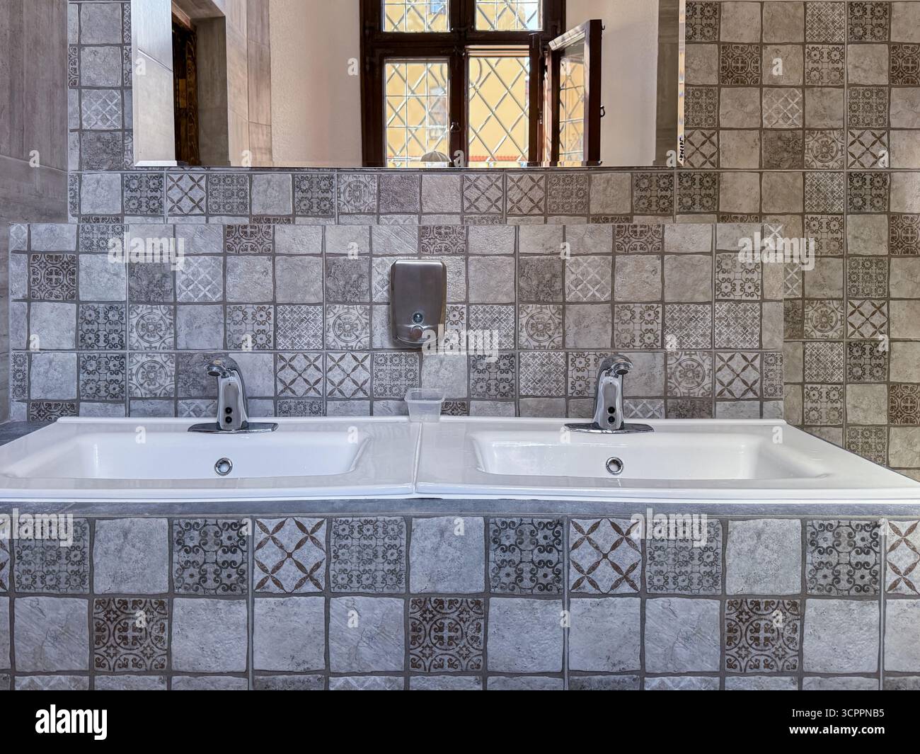 Modern bathroom interior featuring two sinks, mirrors, and decorative geometric tiles, showcasing contemporary design and clean lines - Smartphone Captured Stock Image