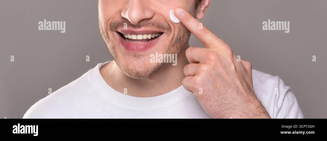 Smiling man moisturizing face with crea,. close up portrait Stock Photo
