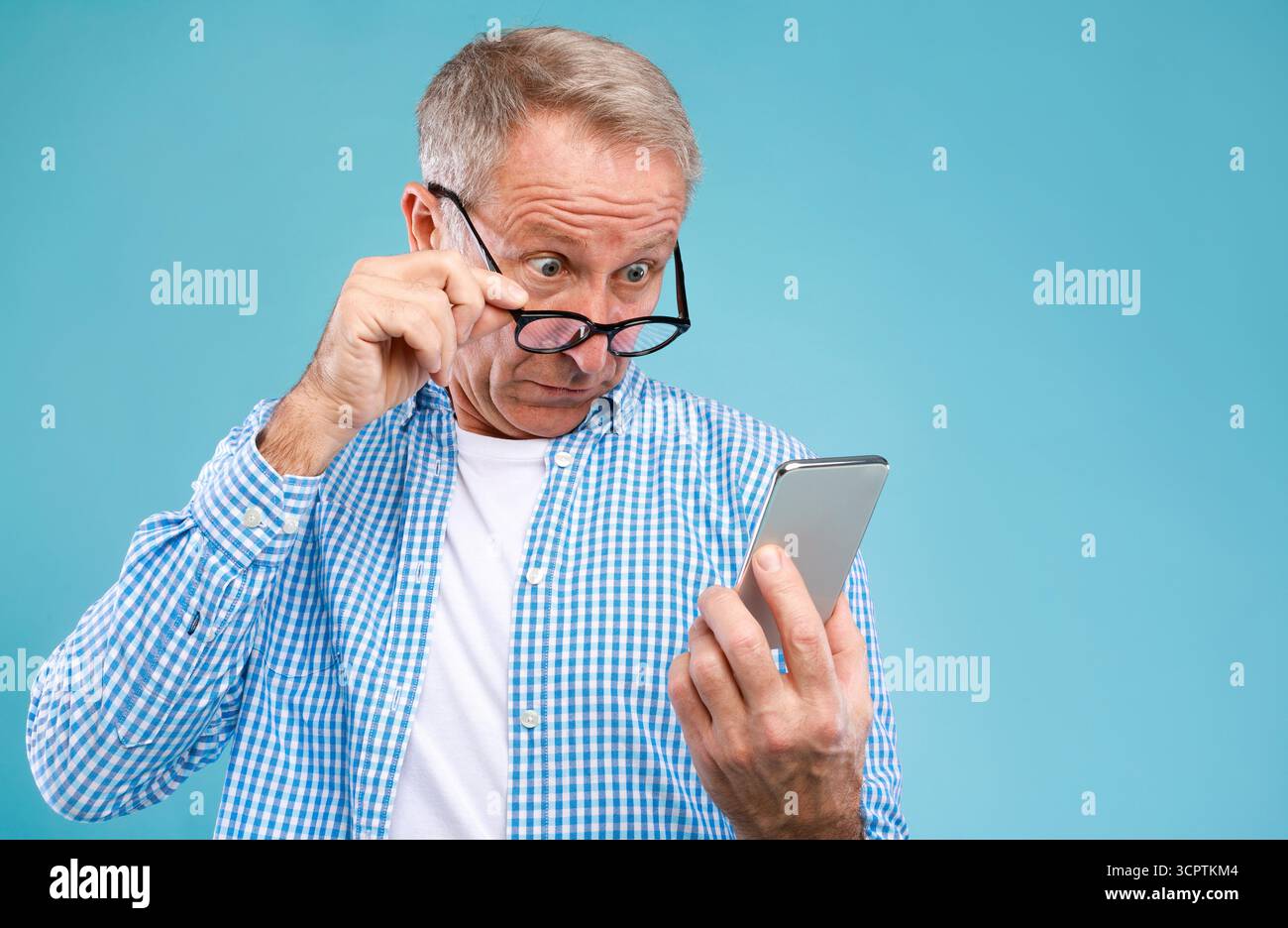Surprised mature man using mobile phone, looking at screen Stock Photo
