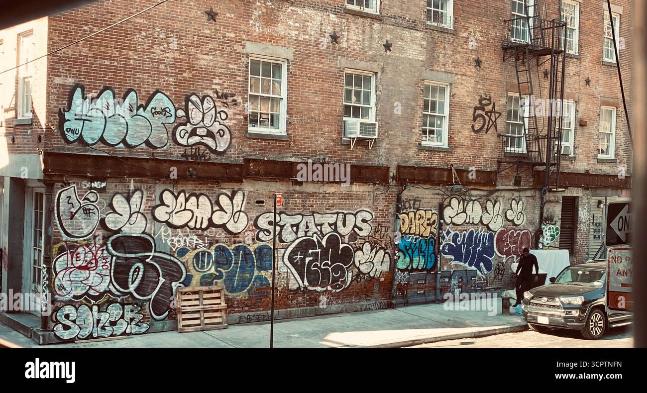 Graffitied Brick Building with Fire Escape and Street Scene in New York City - Smartphone Captured Stock Image