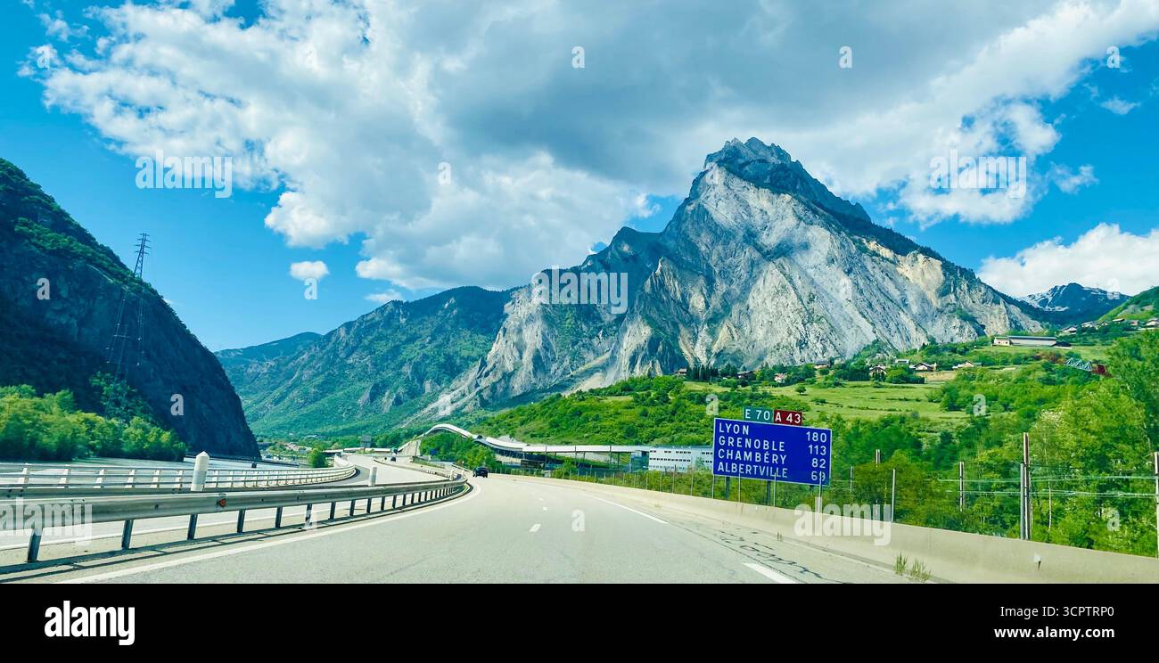 Mountain Highway Scene with Road Sign and Rocky Cliffs under Partly Cloudy Sky in France - Smartphone Captured Stock Image