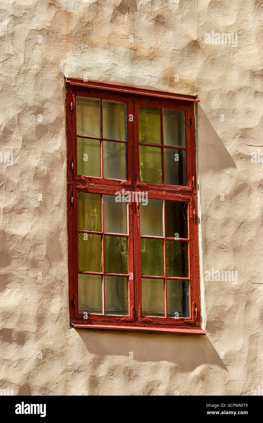 Red window on a white wall with shadows Stock Photo