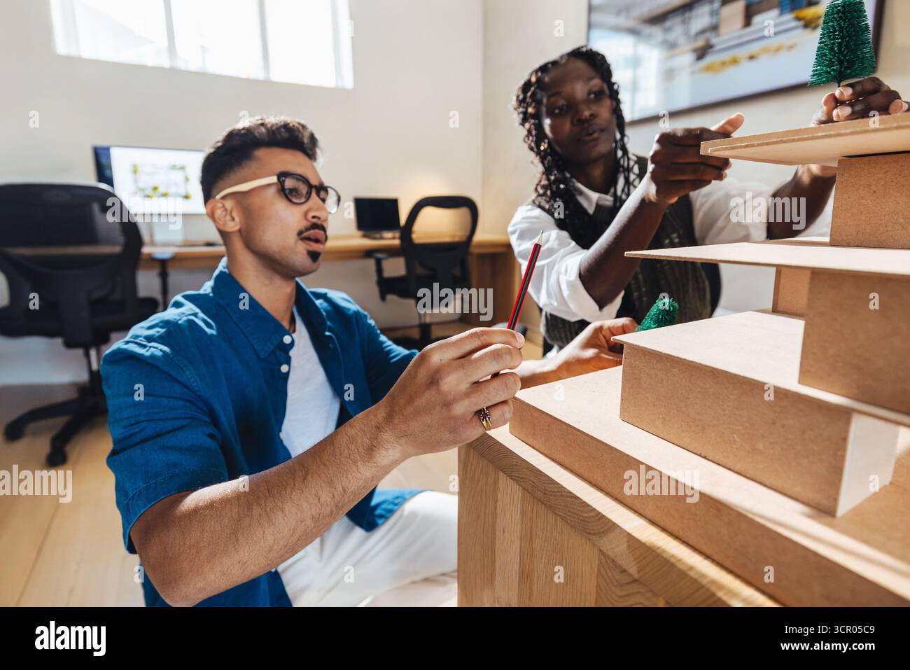 Two architects working together designing a detailed project model in a ...