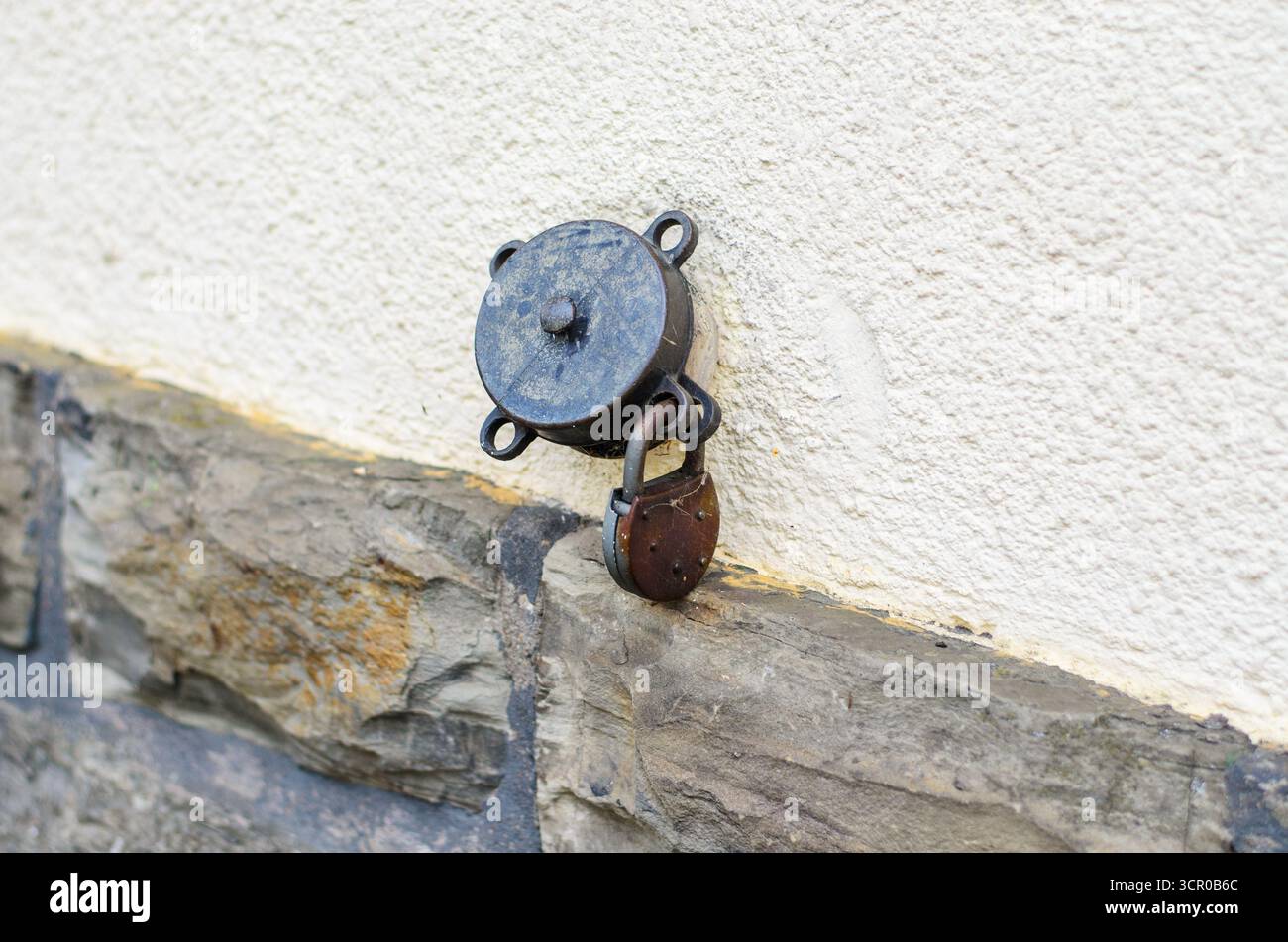 Rusty lock hanging on wall bracket old security system Stock Photo