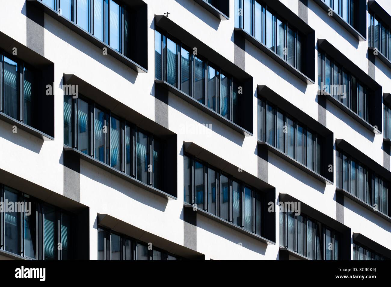 Contemporary office building with vertical window rhythm and clean white facade under clear bright blue sky Stock Photo