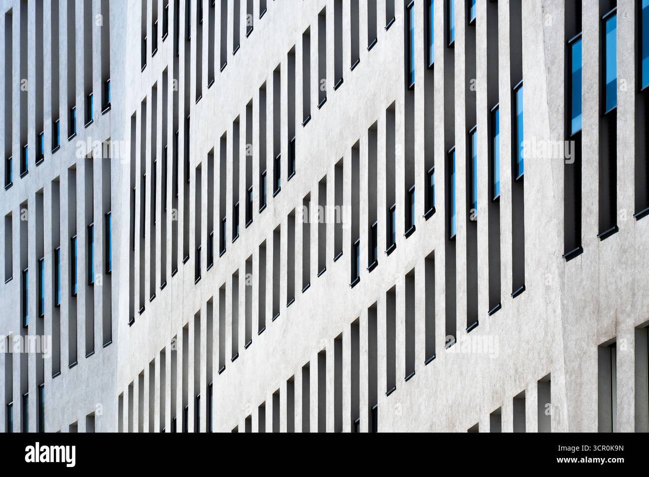Contemporary office building with vertical window rhythm and clean white facade under clear bright blue sky Stock Photo