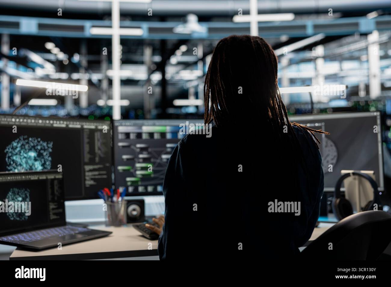 Data center technician uses AI visualization tool on computer to oversee automated repetitive tasks. Worker adapting server systems based on data analytics graphs using desktop PC Stock Photo