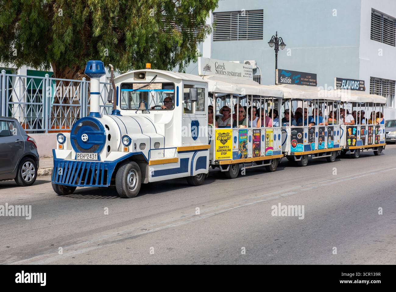 tourists and visitors to the Greek island of Zante or Zakynthos town riding on a small tourist train connecting the town to the coastal holiday resort Stock Photo