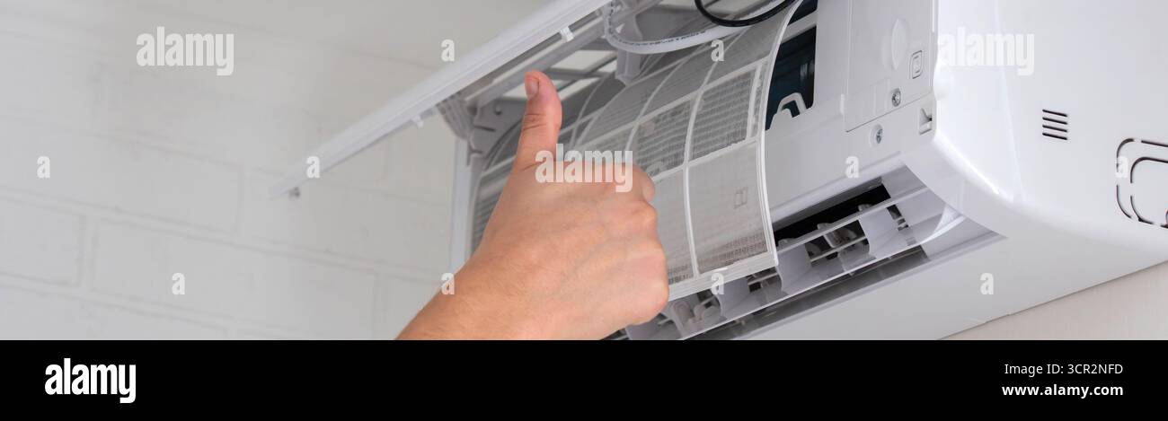 Maintenance Complete. Technician Installing Clean Air Filter in Air Conditioner. Stock Photo