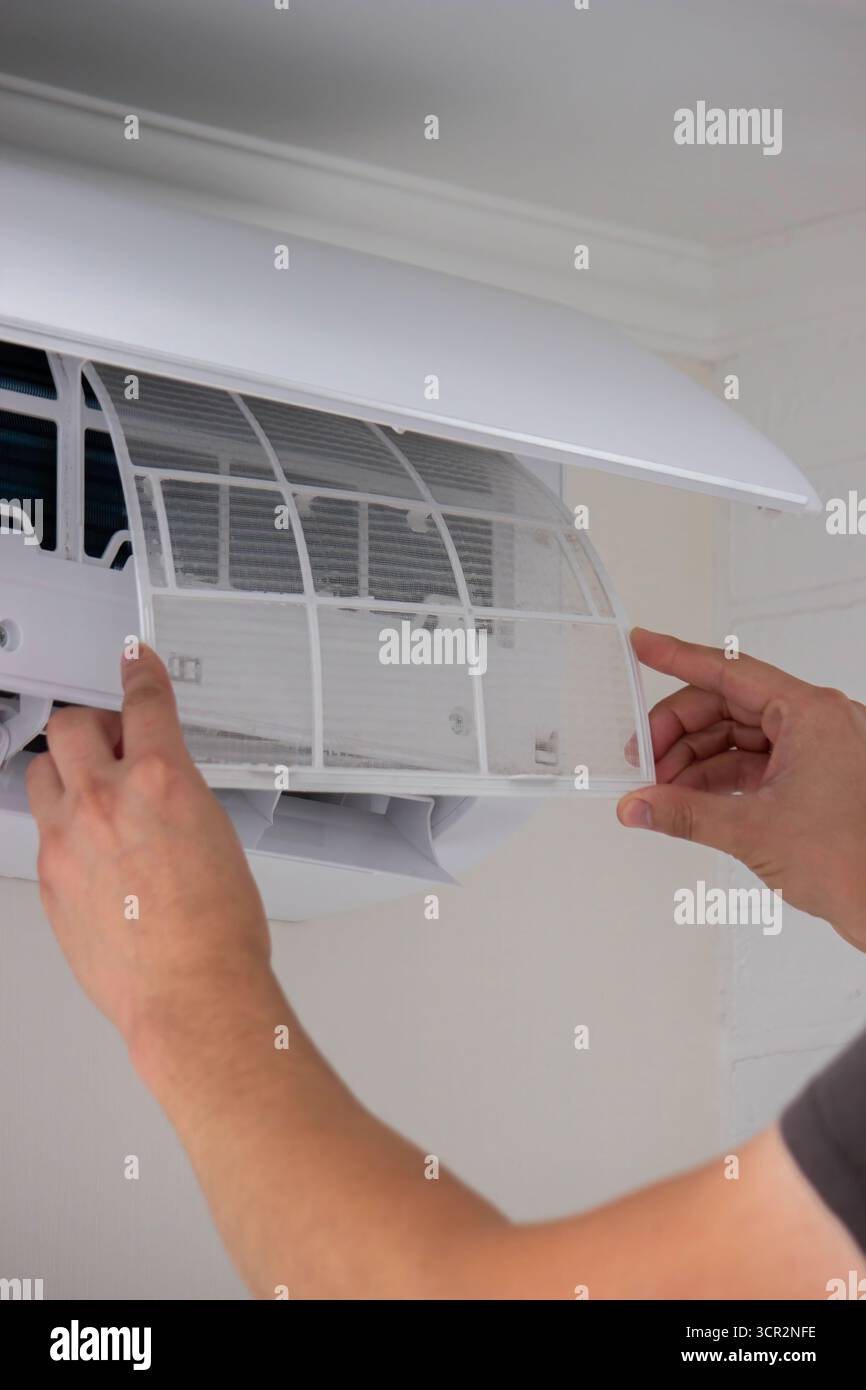 Maintenance Complete. Technician Installing Clean Air Filter in Air Conditioner. Stock Photo