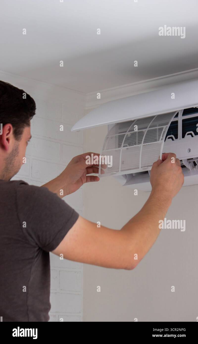 Maintenance Complete. Technician Installing Clean Air Filter in Air Conditioner. Stock Photo