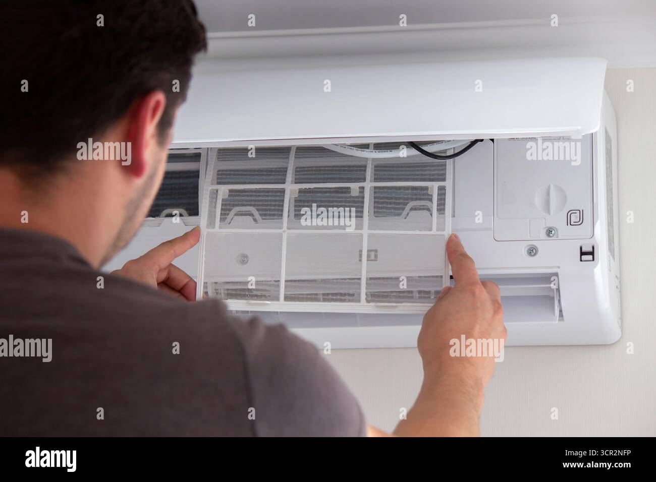 Maintenance Complete. Technician Installing Clean Air Filter in Air Conditioner. Stock Photo