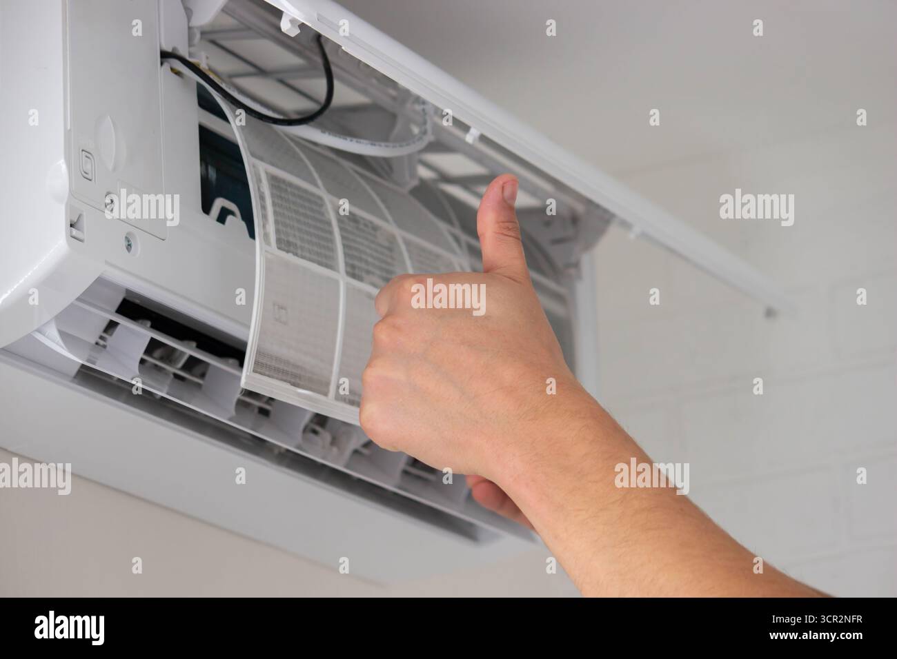 Maintenance Complete. Technician Installing Clean Air Filter in Air Conditioner. Stock Photo