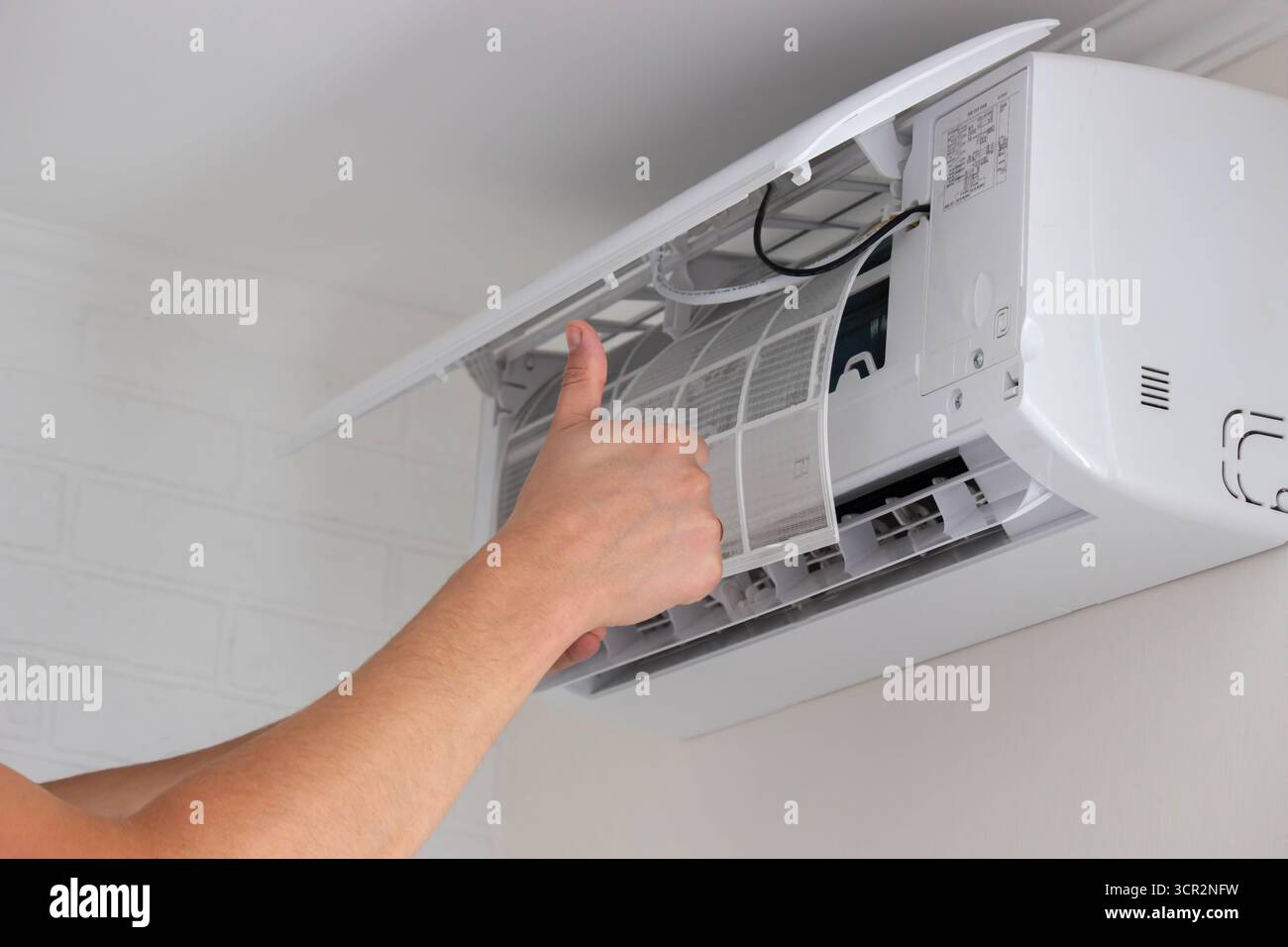 Maintenance Complete. Technician Installing Clean Air Filter in Air Conditioner. Stock Photo