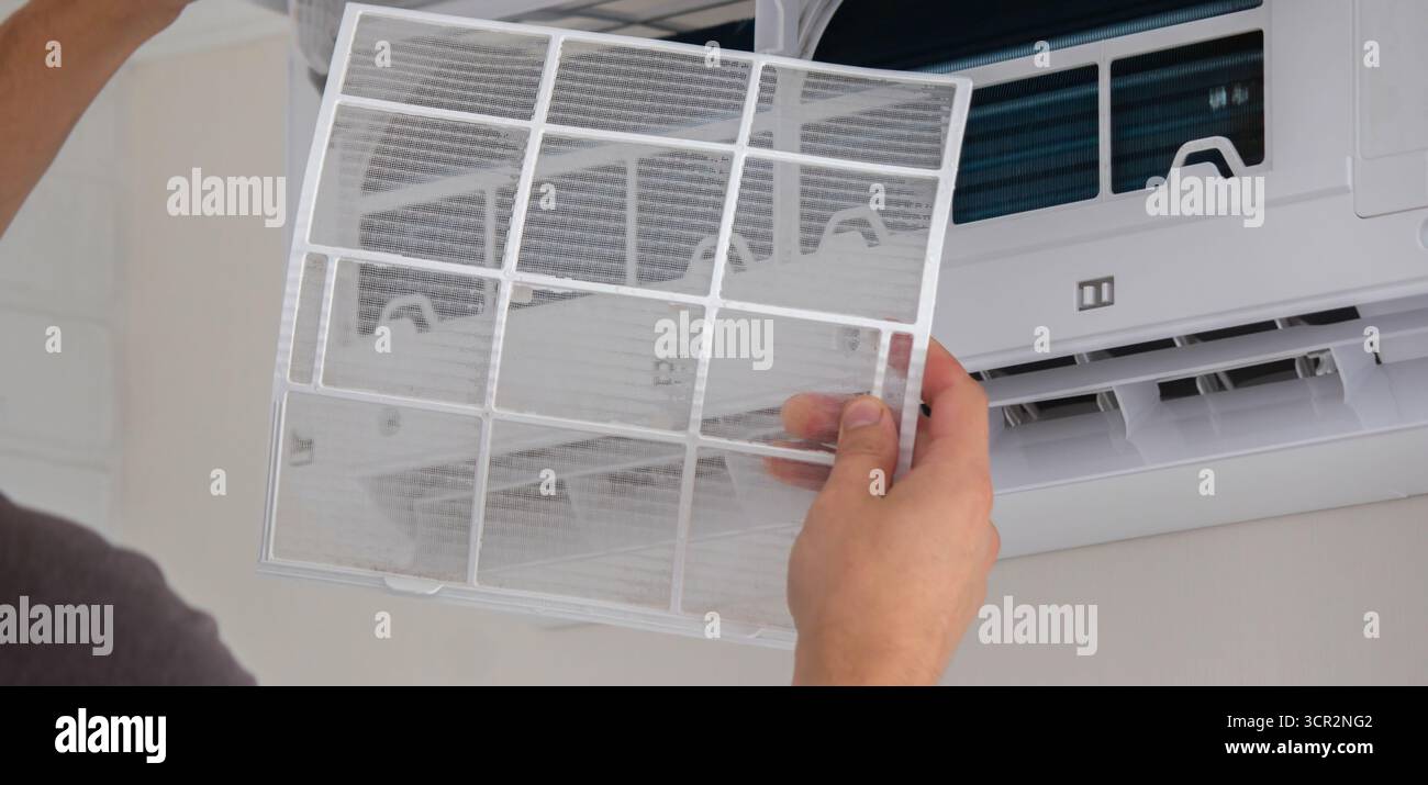 Maintenance Complete. Technician Installing Clean Air Filter in Air Conditioner. Stock Photo