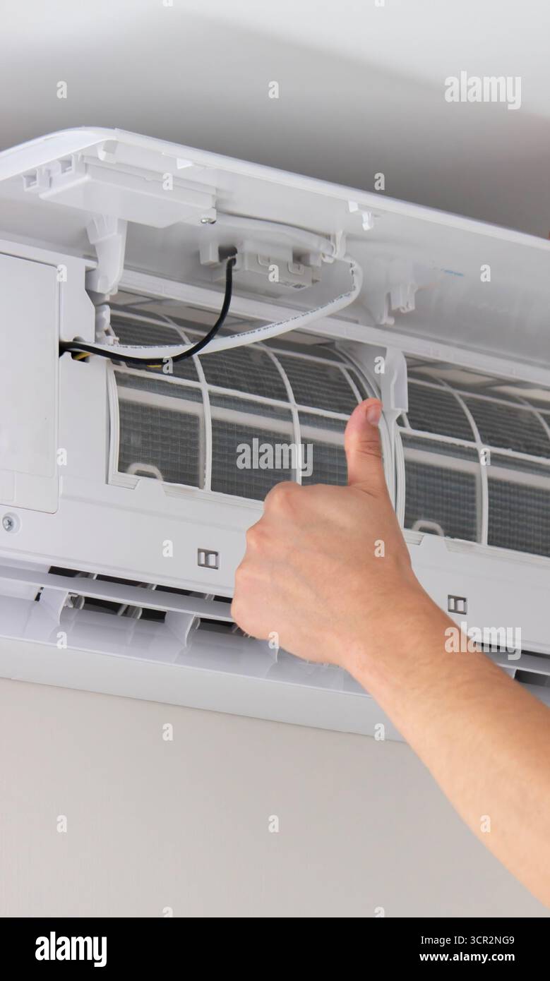 Maintenance Complete. Technician Installing Clean Air Filter in Air Conditioner. Stock Photo