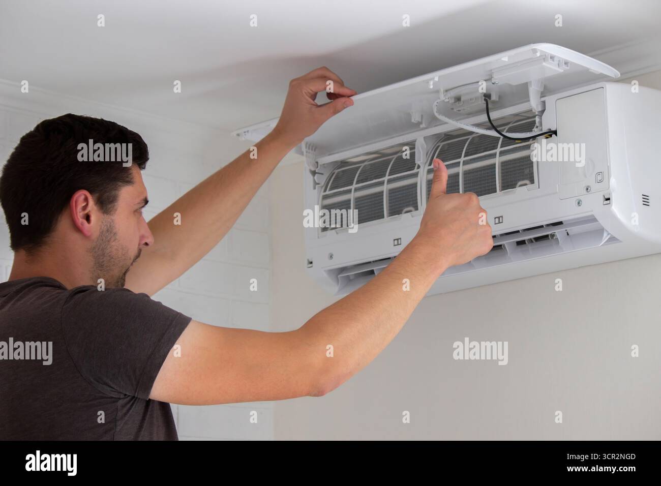 Maintenance Complete. Technician Installing Clean Air Filter in Air Conditioner. Stock Photo