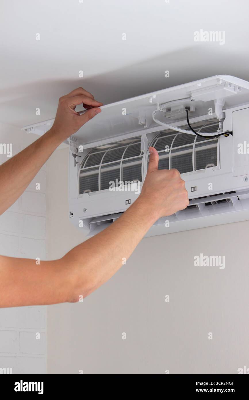 Maintenance Complete. Technician Installing Clean Air Filter in Air Conditioner. Stock Photo