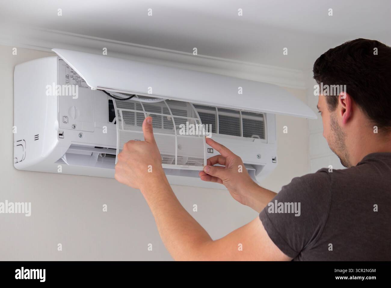 Maintenance Complete. Technician Installing Clean Air Filter in Air Conditioner. Stock Photo