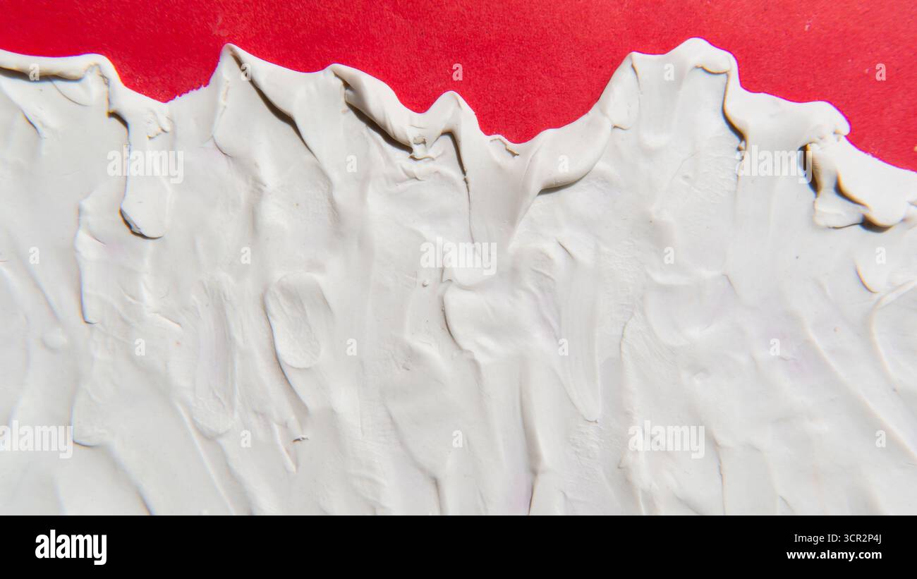 White modelling clay pressed onto a red paper texture background Stock Photo