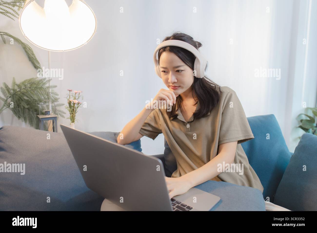 A young woman wearing headphones interacts with her laptop in different ...