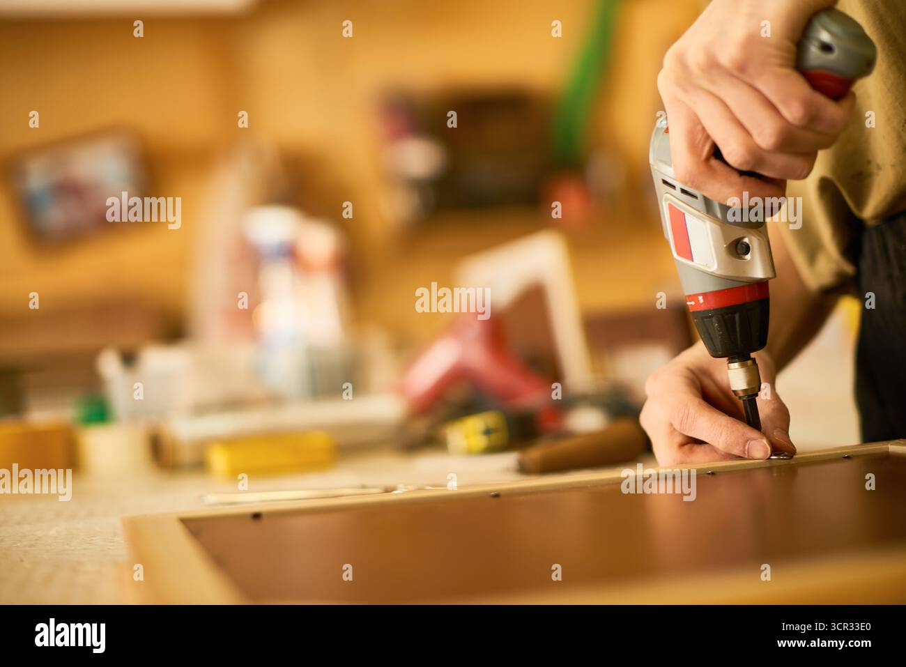 Man Assembling Furniture Using Electric Screwdriver Stock Photo