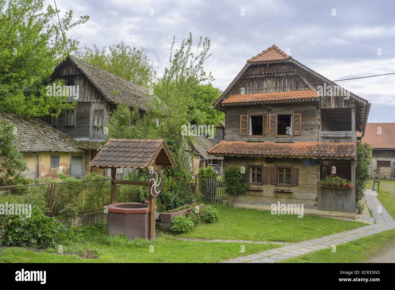 Old wooden house with well, Cigoc, Sisak-Moslavina County, Croatia Stock Photo