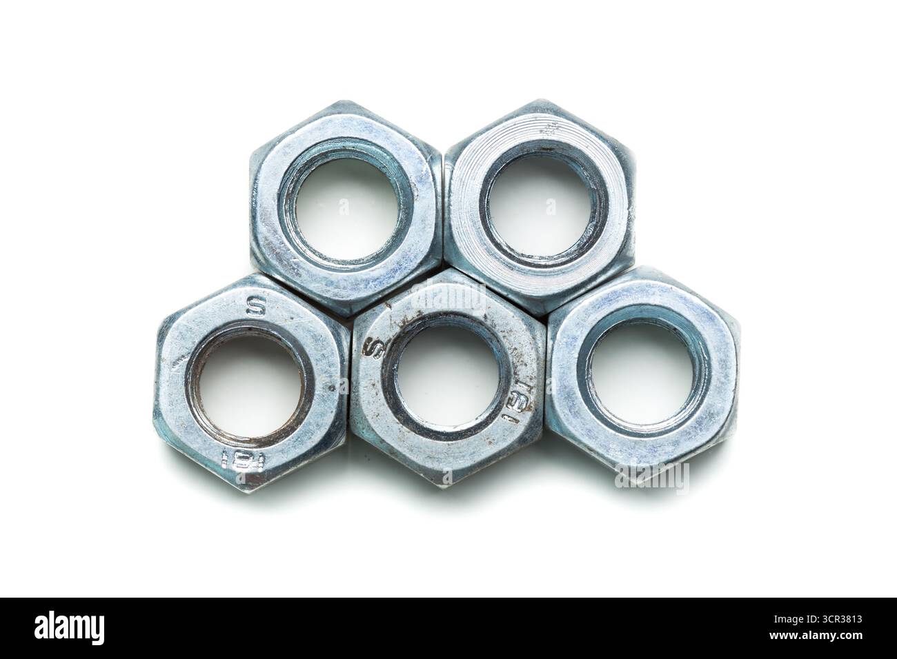 Metal nuts arranged in a stack, showcasing their hexagonal shape and shiny surface Stock Photo