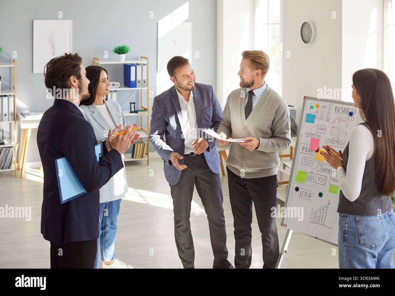 Cheerful business professionals discussing ideas and analyzing plans during team meeting in office. Stock Photo