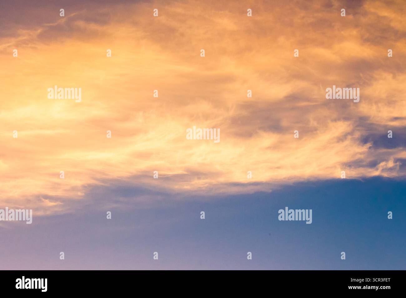 orange cloud on blue sky at sunset. beautiful nature background at dusk for meteorology. cloudscape in yellow light. abstract scene of summer weather Stock Photo