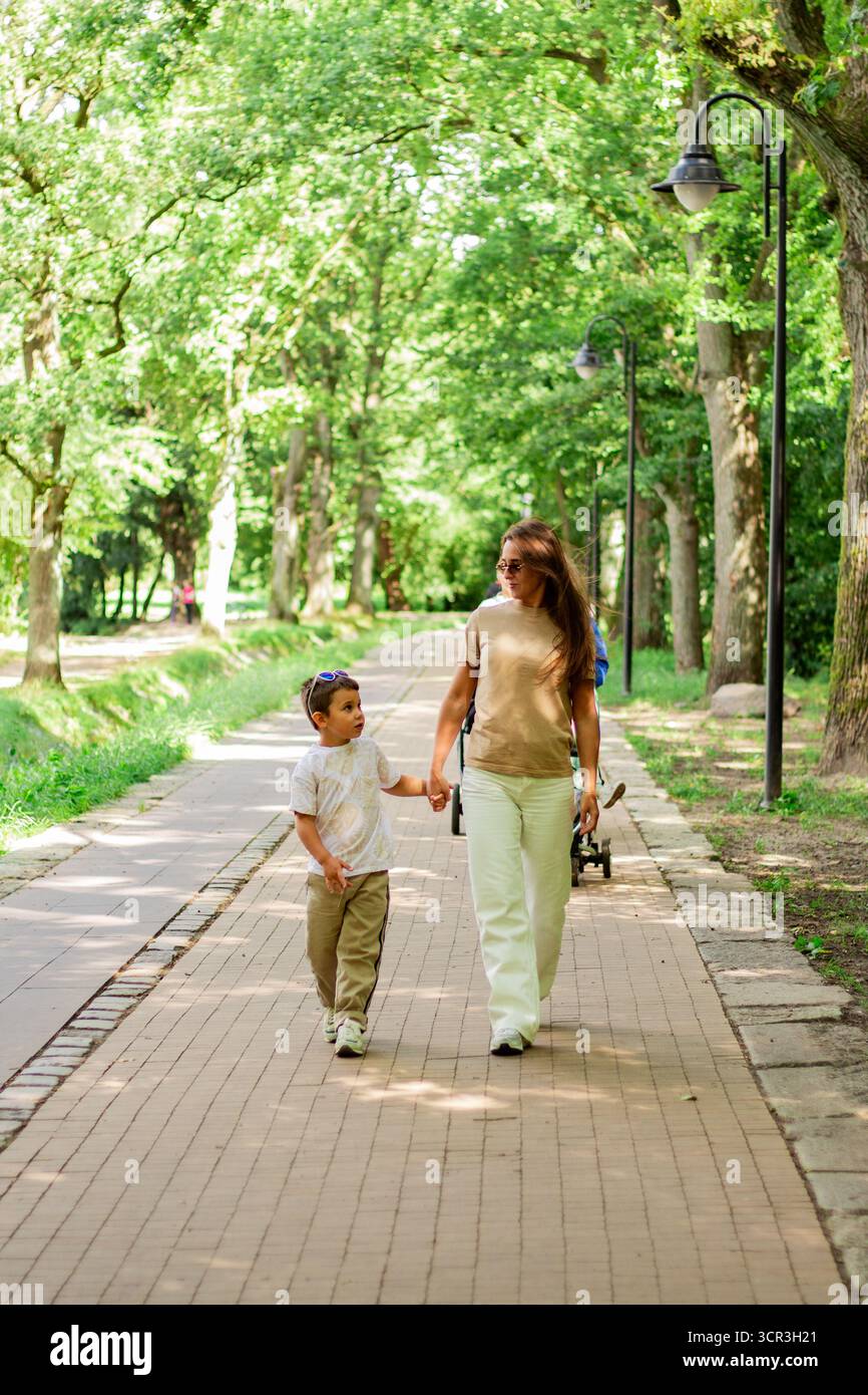 Caucasian mother and son enjoy leisure time in park walking and talking, smiling laughing. Serene family connection. Stock Photo