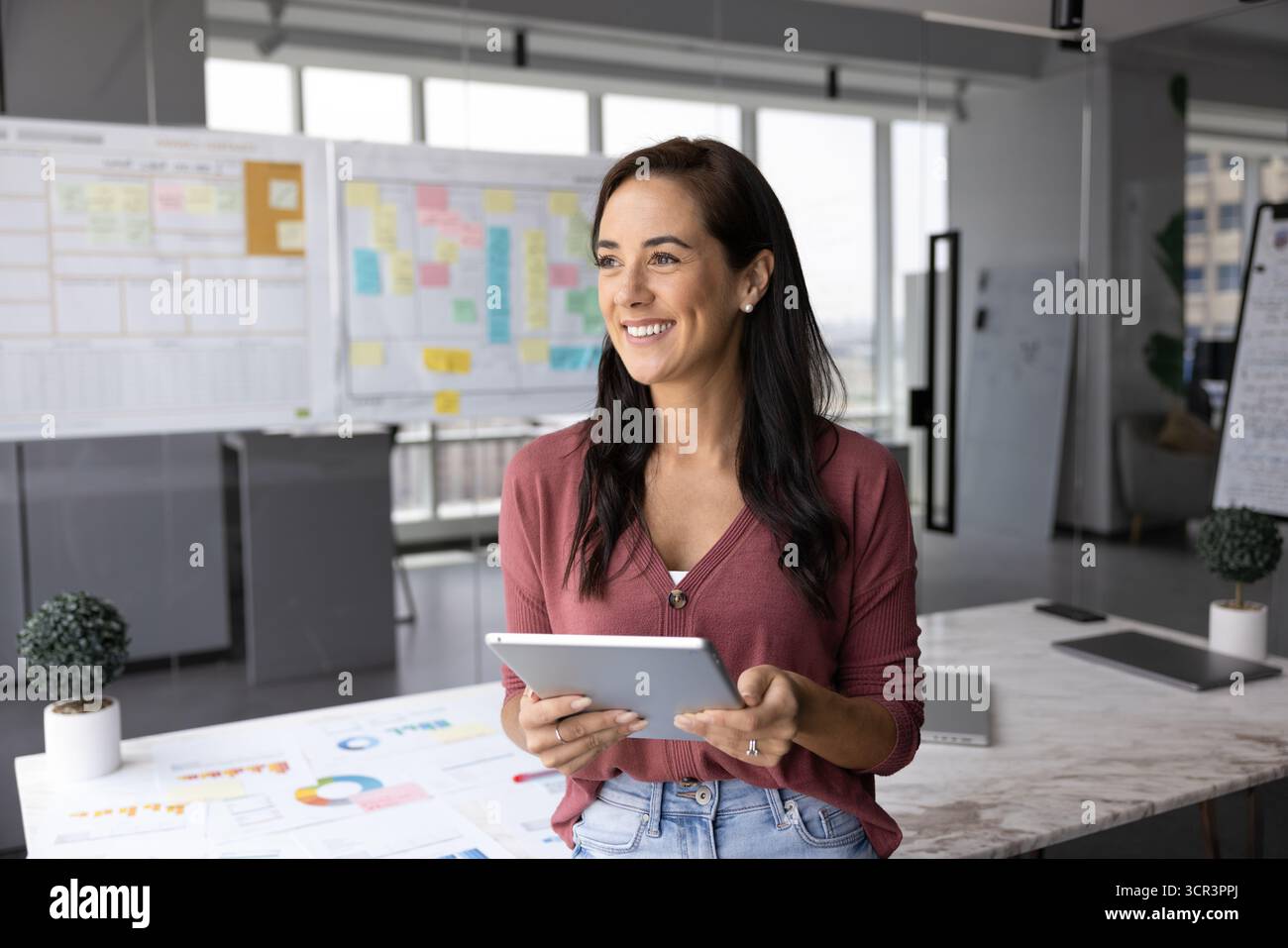 Happy professional woman standing in office with tablet Stock Photo