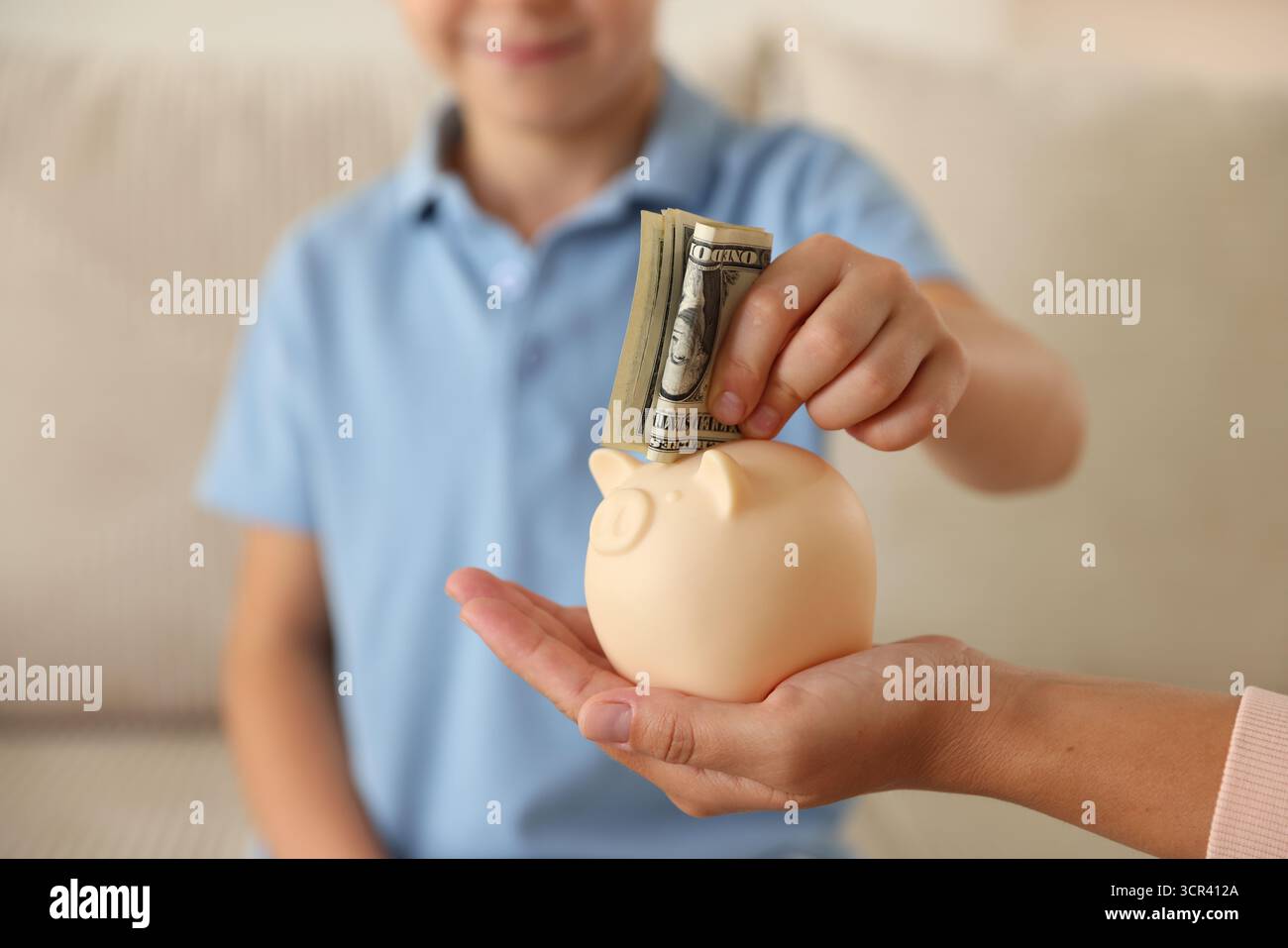 Mother and her son putting pocket money into piggy bank at home ...