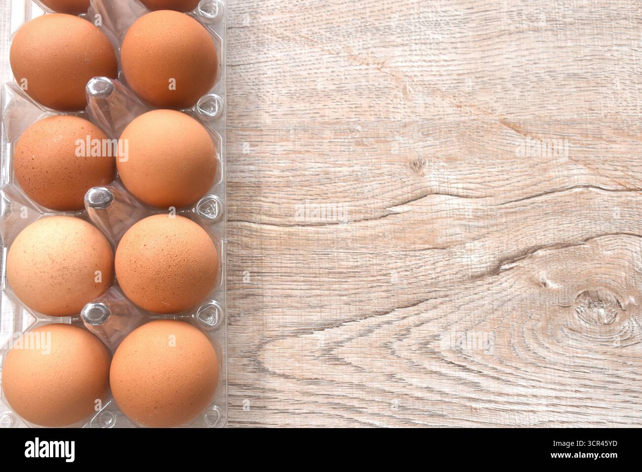 brown raw eggshell arranging in transparent plastic packing on wooden table Stock Photo