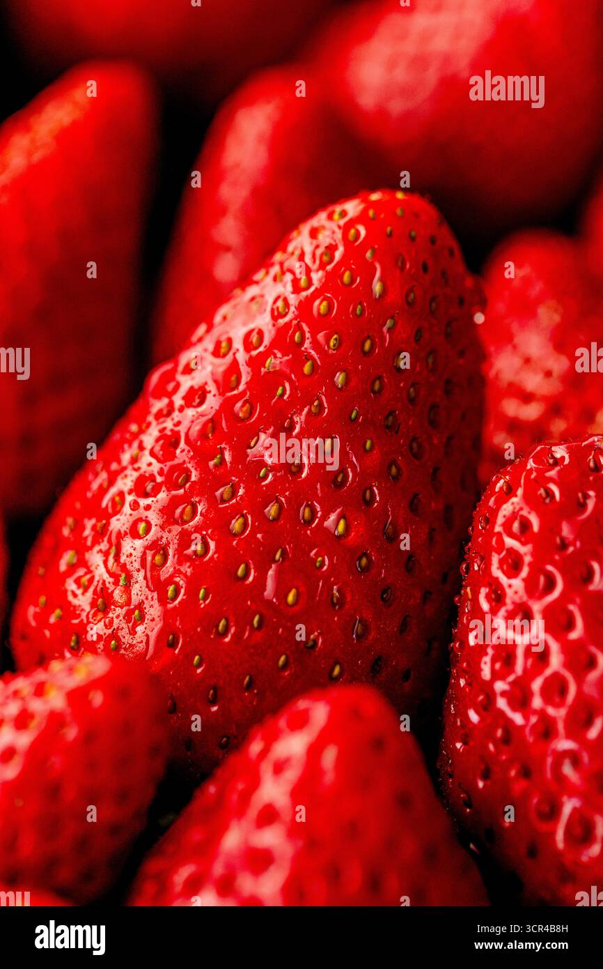 Extreme macro of strawberry skin and seeds with glossy highlights. Stock Photo