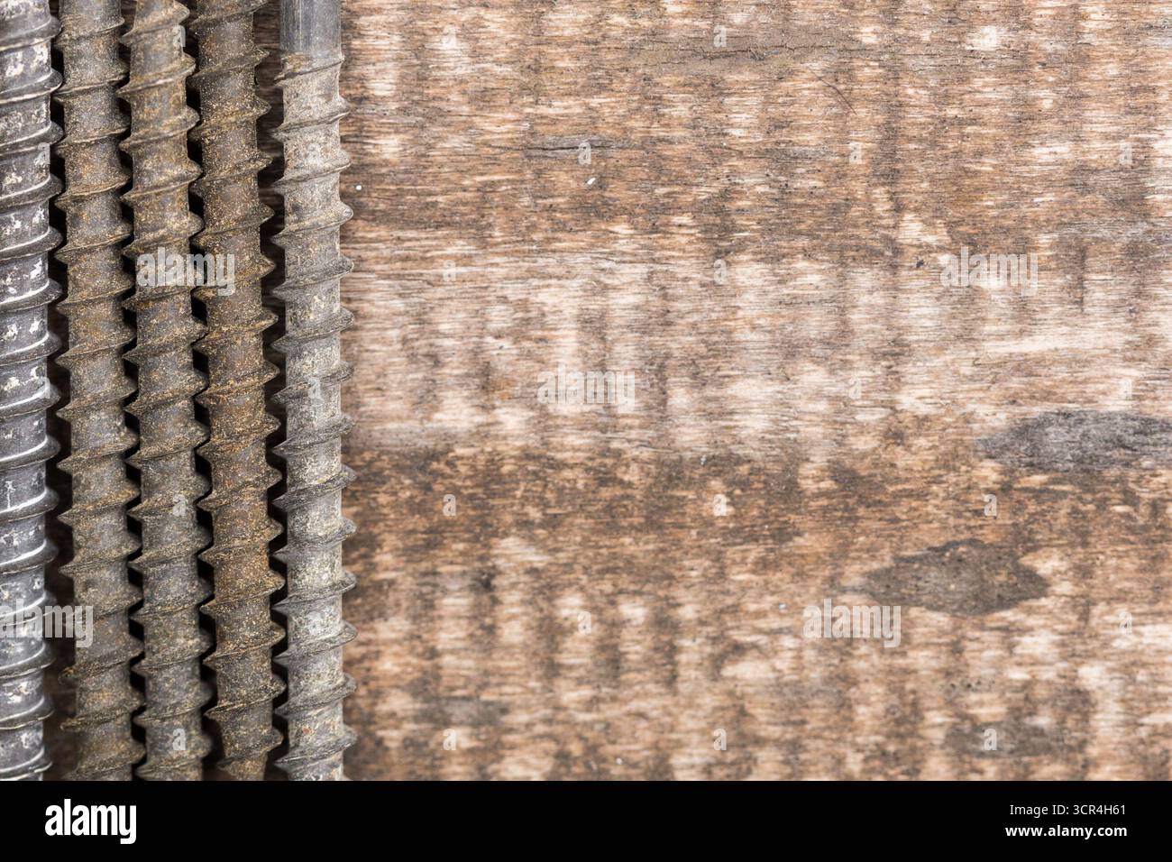 Close-up view of screws arranged on rustic wooden surface with visible grain Stock Photo