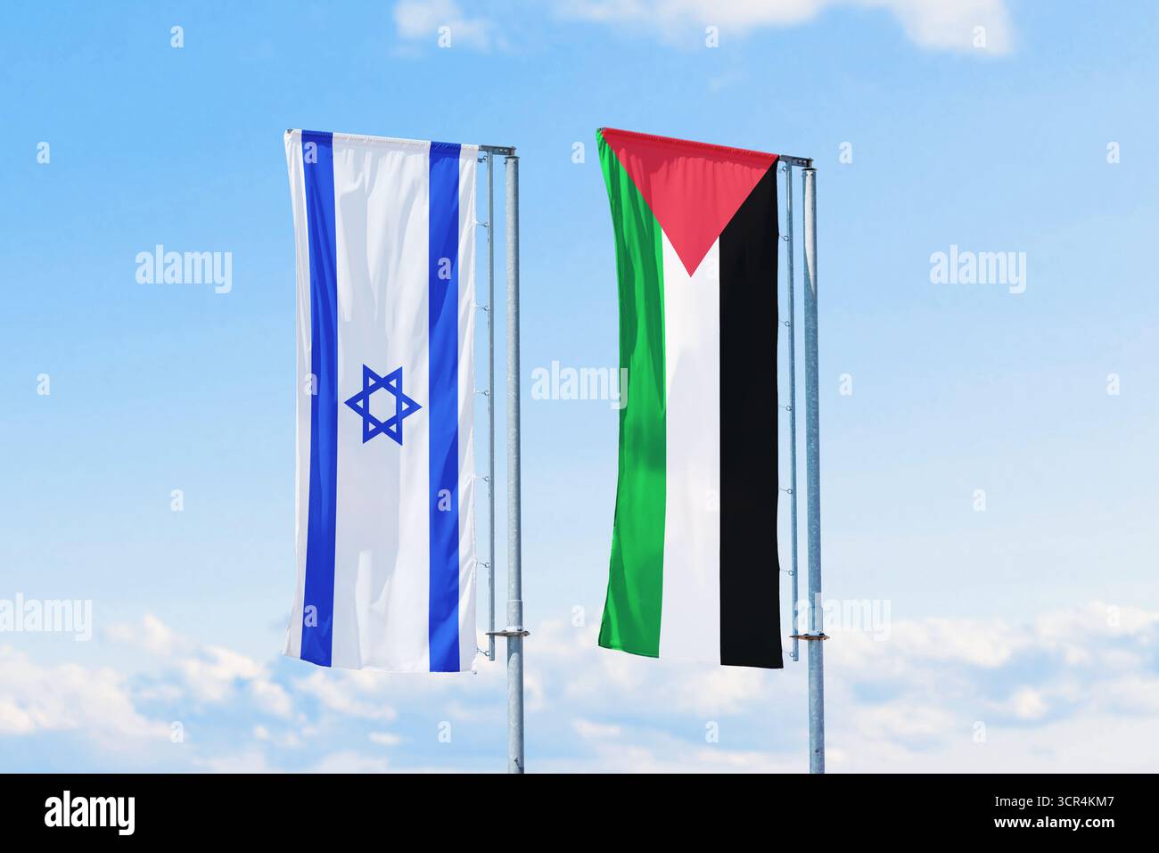 Israel and Palestine flags waving side by side on tall poles against blue sky, international conflict and peace talks concept. Stock Photo