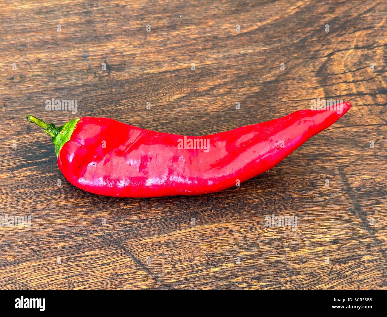 Single Red Chili Pepper on Wooden Table Stock Photo