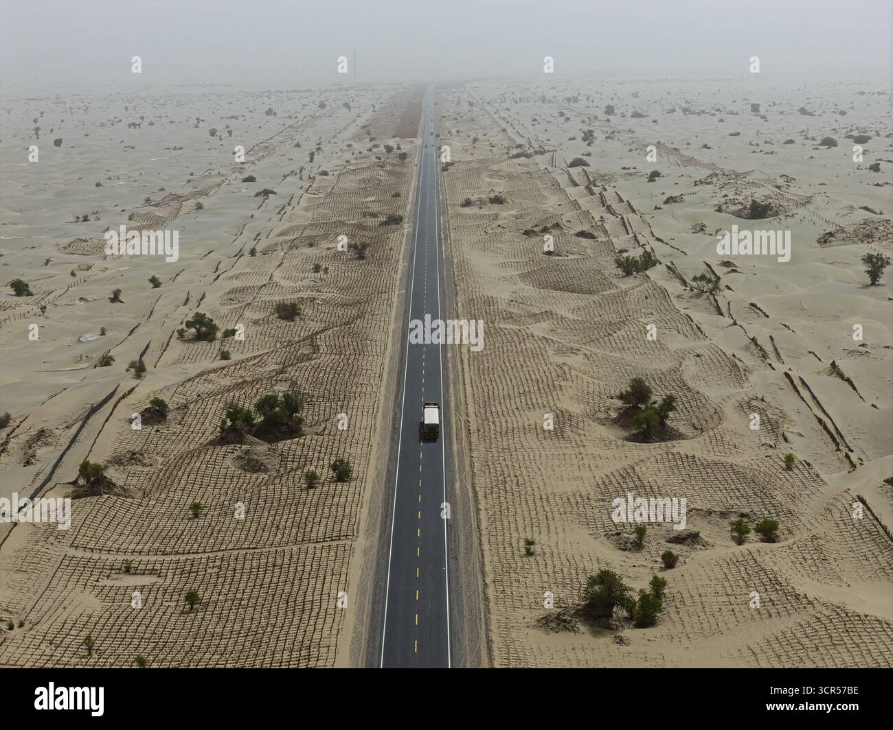 Aerial view of a lone vehicle traversing the stark, endless highway ...