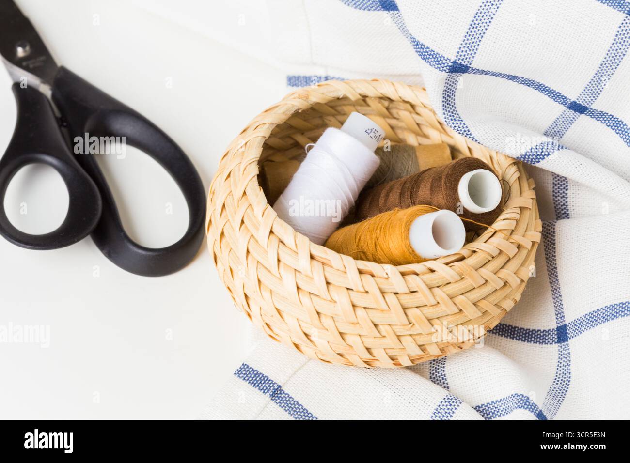 Sewing supplies arranged in a woven basket with scissors on a fabric ...