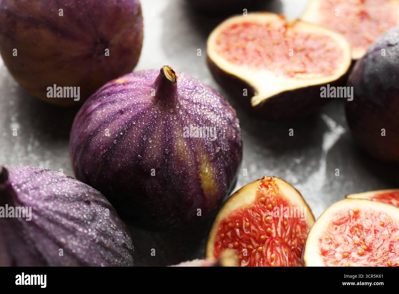 Whole and cut figs on gray table, closeup Stock Photo