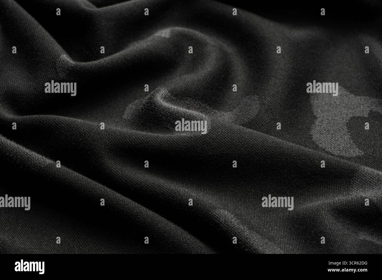 Black, draped fabric with subtle camouflage spots and shallow depth of ...