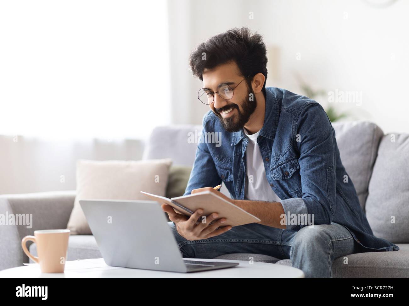 Distance Learning. Indian Man Study With Laptop At Home And Taking Notes Stock Photo