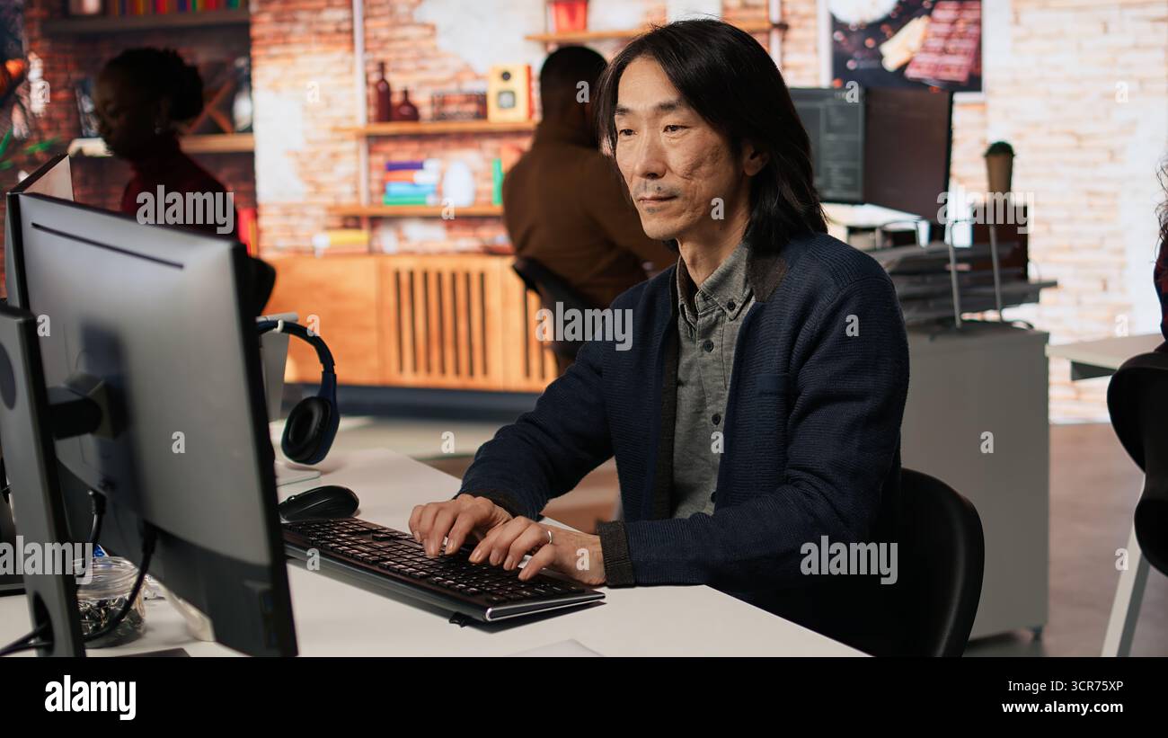 Portrait of smiling senior engineer coding advanced AI algorithm in startup office, refining machine learning models. Cheerful man using coding platform in Silicon Valley workplace, camera A Stock Photo