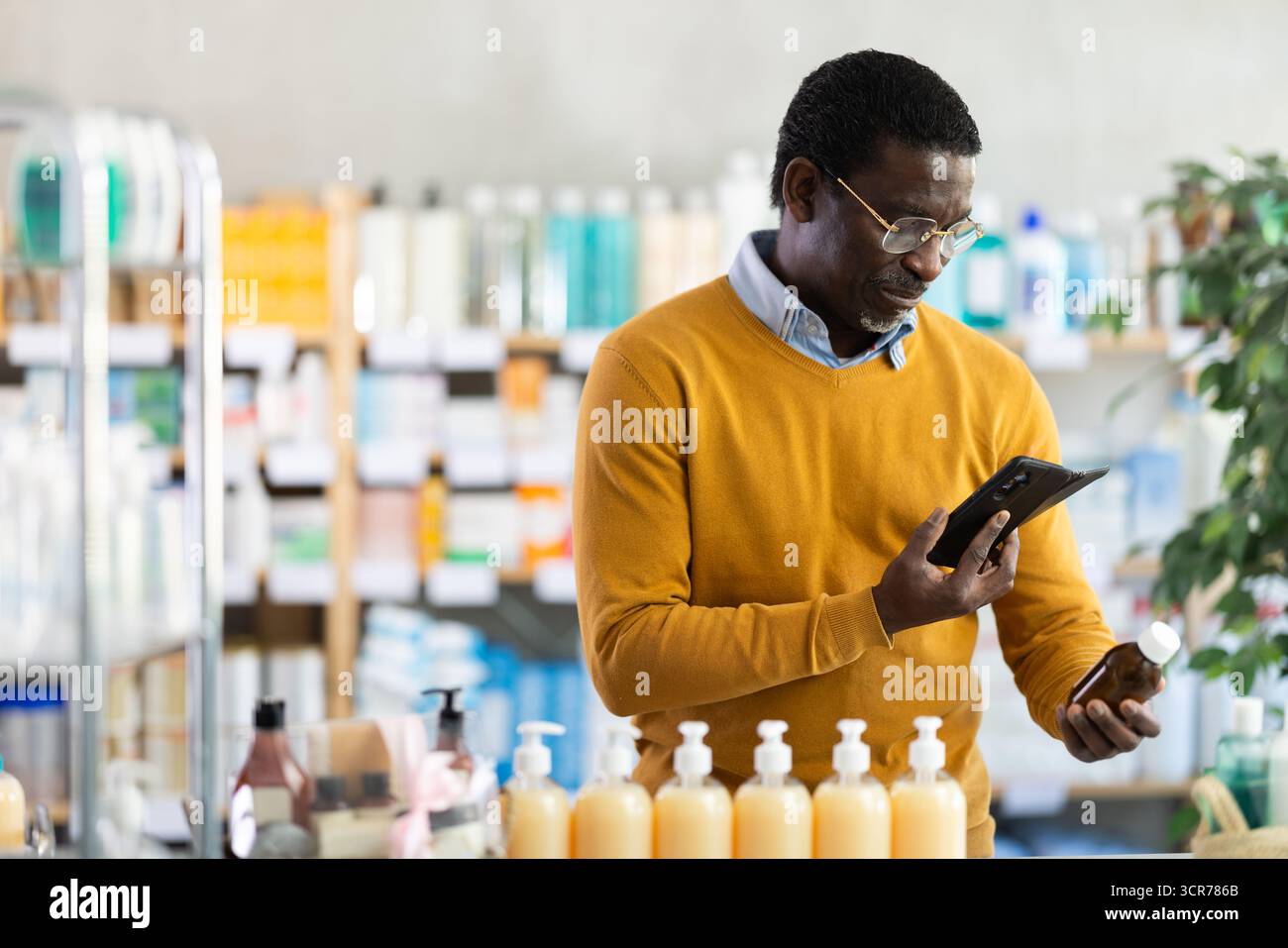 African American man checking syrup medicine details on smartphone Stock Photo