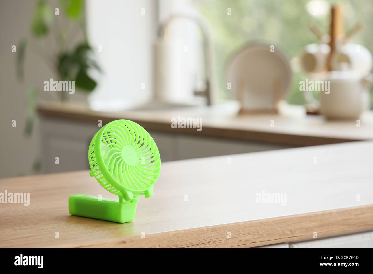 Green mini fan on table in kitchen, closeup Stock Photo