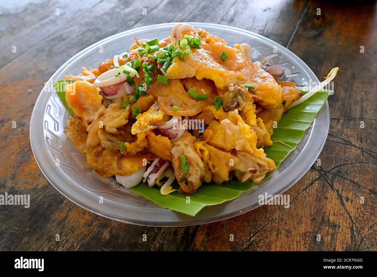 A variation of the popular fried oyster omelette (Hoi Tod) served with mussels and squids on a banana leaf at a floating market food stall in Thailand Stock Photo