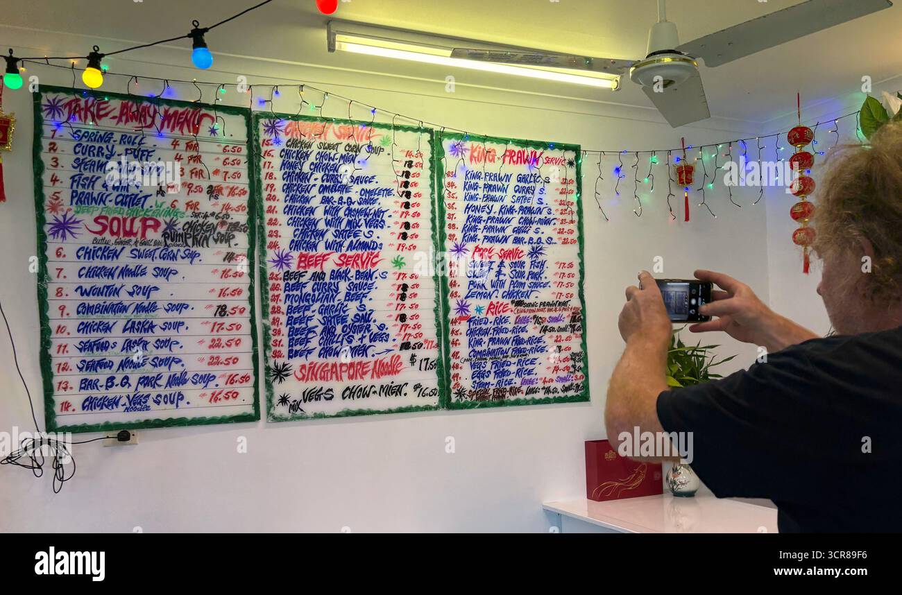 Man using smartphone to take photo of wall menu in Chinese restaurant, Cairns, Queensland, Australia. No MR or PR - Smartphone Captured Stock Image
