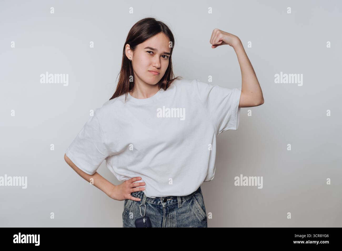 Strong young woman poses confidently while showing off her muscles in a casual indoor setting Stock Photo