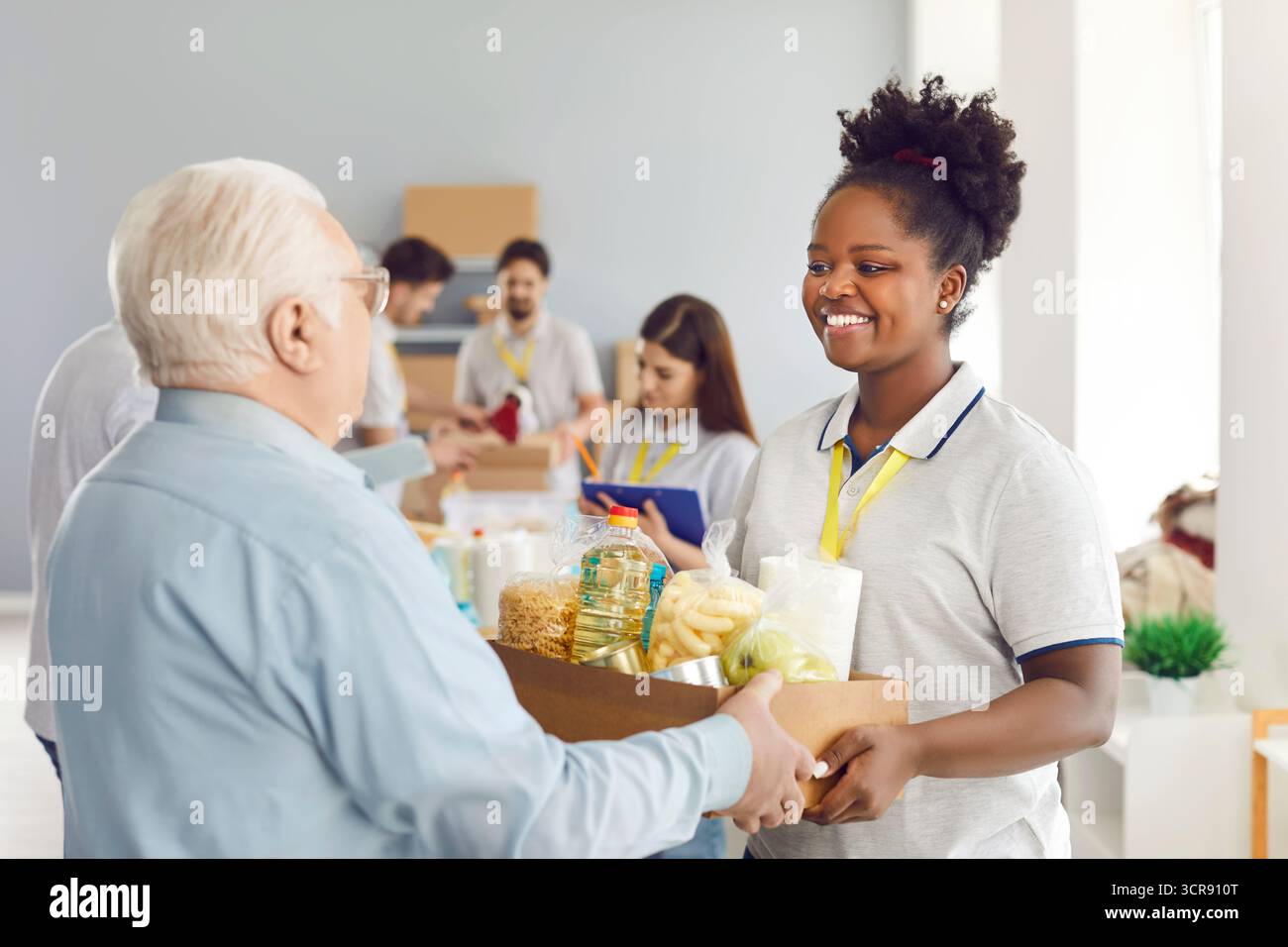 African American woman volunteer giving food box to elderly man, close ...